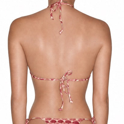 Rear view of a model wearing a pink and white patterned string bikini bottom with a halter-style top, shown against a plain white background.