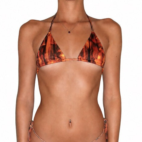 A model wearing a string bikini with a fiery orange, red, and black abstract pattern, shown against a plain white background.